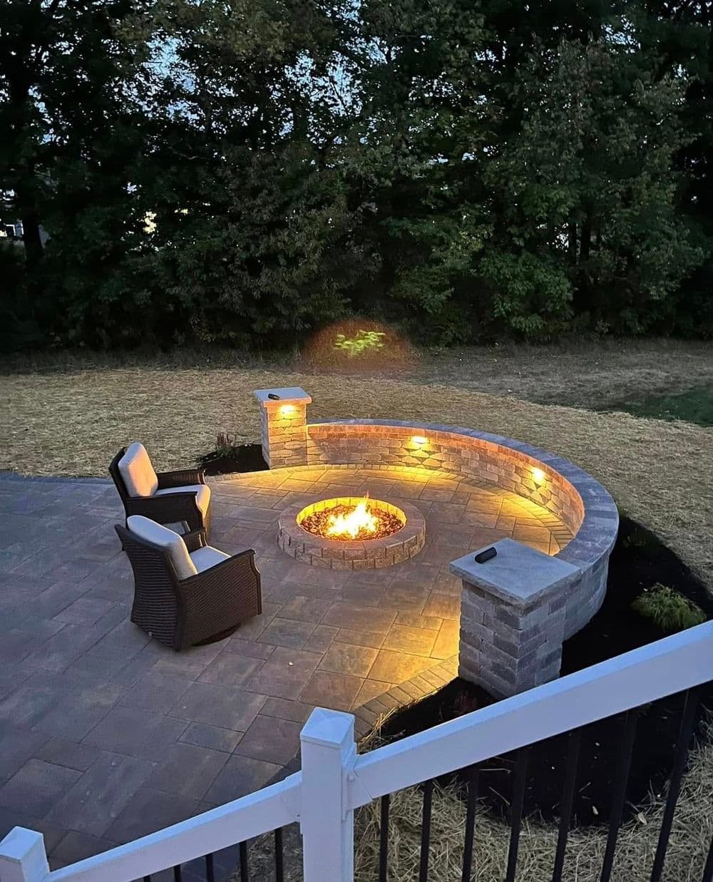 Cozy backyard fire pit with lighting and seating in a serene outdoor setting.