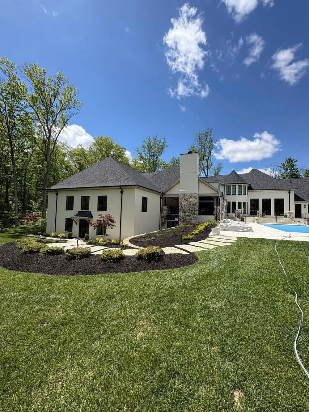Stunning luxury home with landscaped yard and pool under a blue sky.